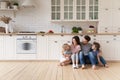 Happy family with children sitting on floor in modern kitchen Royalty Free Stock Photo