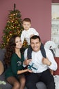 Happy family in Christmas interior. Beautiful mother, handsome father and a cute baby boy sitting on sofa in the living Royalty Free Stock Photo