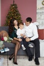 Happy family in Christmas interior. Beautiful mother, handsome father and a cute baby boy sitting on sofa in the living Royalty Free Stock Photo