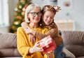 Happy family on Christmas morning. Affectionate grandmother and cheerful granddaughter open a holiday gift together Royalty Free Stock Photo
