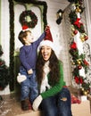 Happy family on Christmas in red santas hats waiting gests and smiling infront of decorated house, mother and son