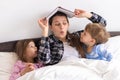 happy family. Close up loving mother lying with daughter son two kids pajamas in bed children reading interesting Royalty Free Stock Photo