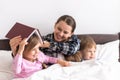 happy family. Close up loving mother lying with daughter son two kids pajamas in bed children reading interesting Royalty Free Stock Photo