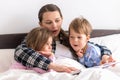 happy family. Close up loving mother lying with daughter son two kids pajamas in bed children reading interesting Royalty Free Stock Photo