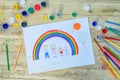 Happy family concept. Drawing on wooden table: father, mother, boy and girl hold hands against background of rainbow and sunny sky