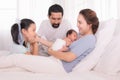 Happy family concept, father and daughter sit on bed excited looking new member in family, adorable newborn sleep on mother chest Royalty Free Stock Photo