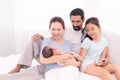 Happy family concept, father and daughter sit on bed excited looking new member in family, adorable newborn sleep on mother chest Royalty Free Stock Photo