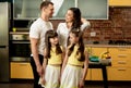 Happy family concept. Father, mother and two adorable daughters posing in the kitchen, smiling and look at each other Royalty Free Stock Photo