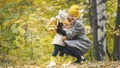 Little daughter with her mommy plays with yellow leaves in autumn park Royalty Free Stock Photo