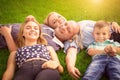 Happy family concept. Mother, father, sun and daughter outdoors lying on grass loan sun flare on right in a sunny day Royalty Free Stock Photo