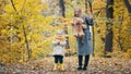 Pretty little daughter with her mommy plays with yellow leaves in autumn park Royalty Free Stock Photo