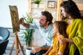 Happy family concept. Young parents with children painting together at home. People fun happyiness.