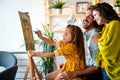 Happy family concept. Young parents with children painting together at home. People fun happyiness.