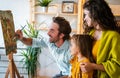 Happy family concept. Young parents with children painting together at home. People fun happyiness.