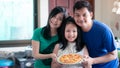 The happy family consisted of father, mother and daughter holding homemade pizza pans in the home kitchen