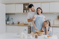 Happy family cook together at kitchen. Father, mother and dauther busy preparing delicious meal at home. Husband embraces wife who