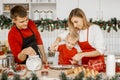 Happy family cooking Christmas cookies in the kitchen. Young smiling mother help her little son sprinkle flour on the dough. Royalty Free Stock Photo