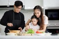 Happy family cooking at kitchen, father mother and cute daughter girl having fun during making meal at home. Parents and kid child Royalty Free Stock Photo