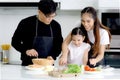 Happy family cooking at kitchen, father mother and cute daughter girl having fun during making meal at home. Parents and kid child Royalty Free Stock Photo