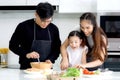 Happy family cooking at kitchen, father mother and cute daughter girl having fun during making meal at home. Parents and kid child Royalty Free Stock Photo