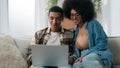 Happy family couple African American husband wife on sofa man woman at couch laptop computer online shopping buying in Royalty Free Stock Photo