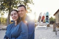 Happy family couple on the beach. Young man hugging beautiful woman on background of surfboards. Husband and wife are surfers Royalty Free Stock Photo