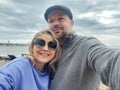 Happy family couple in casual clothes takes selfie on seashore on cloudy day Royalty Free Stock Photo