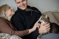 Young family couple with domestic cat and tea cup on sofa at home Royalty Free Stock Photo