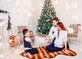 Happy family couple give gifts in the living room, behind the decorated Christmas tree, the light give a cozy atmosphere