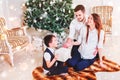 Happy family couple give gifts in the living room, behind the decorated Christmas tree, the light give a cozy atmosphere Royalty Free Stock Photo