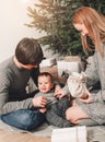 Happy family couple give gifts in the living room, behind the decorated xmas tree, the light give a cozy atmosphere. New Year Royalty Free Stock Photo