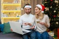 Happy family couple man and woman on Christmas do online shopping in online store sitting on sofa at home near Christmas Royalty Free Stock Photo