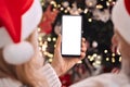 Happy family couple in santa hats using cell phone mockup screen on Christmas. Royalty Free Stock Photo