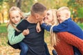 Happy family couple with two children kissing in autumn park