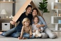 Happy family couple and two skids holding cardboard roof overhead