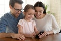 Happy family couple watching funny mobile video with daughter. Royalty Free Stock Photo