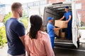 Happy Family Couple Watching Movers Unload Boxes