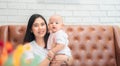 Happy family, Cute Asian newborn baby with young mother smile happy face sitting sofa at home. Innocent little infant adorable. Royalty Free Stock Photo