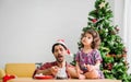 Happy family of cute baby daughter sitting on table and father wear santa hat surprised birthday by cake