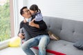 happy family Cute little girl daughter and father are hugging and playing on sofa in living room at home spend time holiday