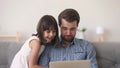 Happy dad and cute child daughter watching cartoons on laptop