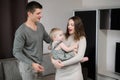 Happy family dancing in the living room holding a toddler in their arms. Concept of hobbies, having fun with children