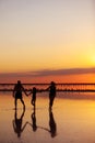 Happy family day. Silhouette of young mom, dad and little daughter holding hands walking together on beach on sunset Royalty Free Stock Photo