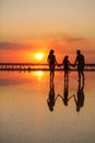 Happy family day. Silhouette of young mom, dad and little daughter holding hands walking together on beach on sunset Royalty Free Stock Photo