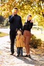 Happy family day. Smiling young mom, dad and little child daughter having fun with fallen maple leaves outdoor at autumn Royalty Free Stock Photo
