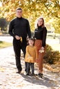 Happy family day. Smiling young mom, dad and little child daughter having fun with fallen maple leaves outdoor at autumn Royalty Free Stock Photo