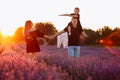 happy family day. Young mother and father carrying on shoulders daughter in lavender field on sunset. Dad, mom and child Royalty Free Stock Photo