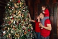 Happy family decorating a Christmas tree with boubles in the living-room.