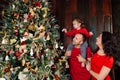 Happy family decorating a Christmas tree with boubles in the living-room.