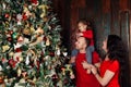 Happy family decorating a Christmas tree with boubles in the living-room.